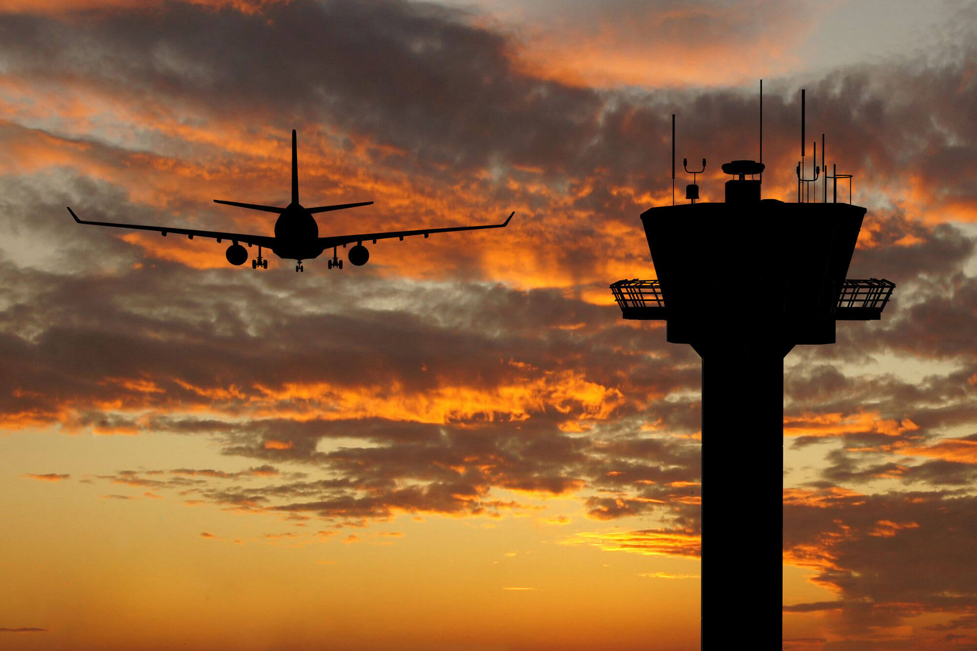 Plane and control tower silhouetted at sunset